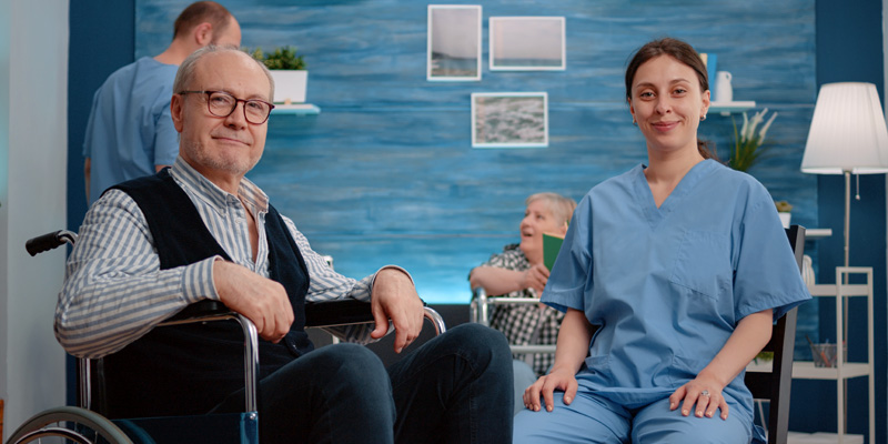 Portrait of disabled senior man sitting with woman nurse
